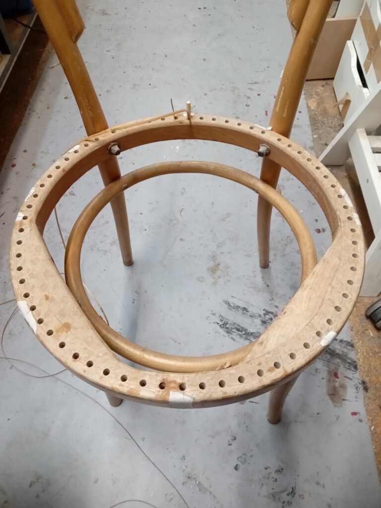 Début cannage traditionnel en cours sur une chaise Thonet, atelier Paris 13