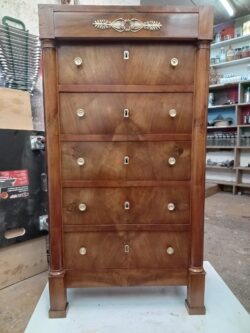 Chiffonier de style Empire en noyer Restauration, reprise de finition, nettoyage des laitons et rebouchages des fissures sur les deux montants. Travail effectué par un artisan dans le XIIIe arrondissement de Paris